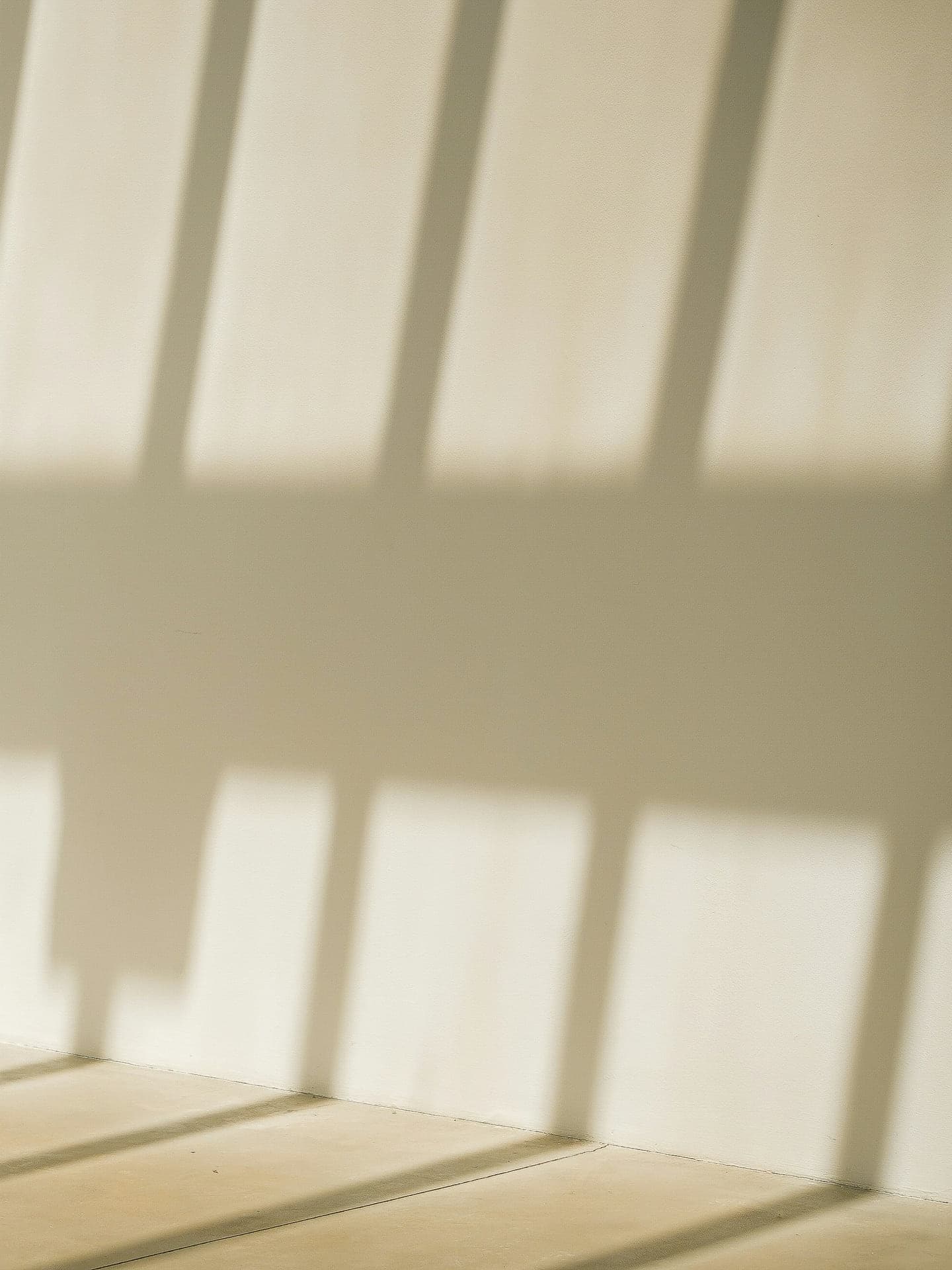 Lege, warme ruimte met strepen zonlicht op een witte muur